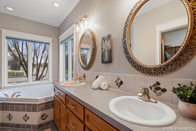 full bathroom with recessed lighting, a garden tub, a sink, and double vanity