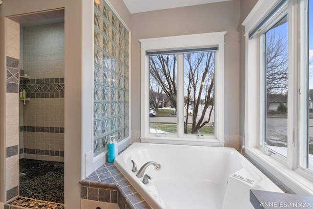 full bathroom with plenty of natural light, a tile shower, and a whirlpool tub