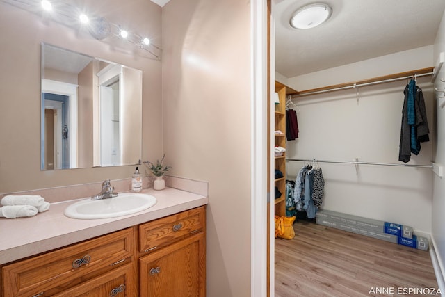 bathroom featuring a spacious closet, wood finished floors, and vanity