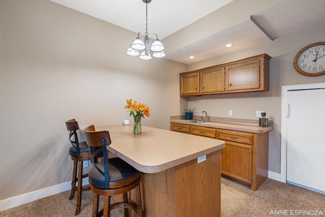 kitchen featuring brown cabinets, a breakfast bar, light countertops, and a sink