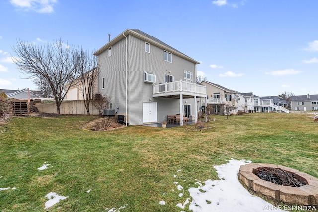 back of house with a deck, a patio area, a lawn, and a fire pit