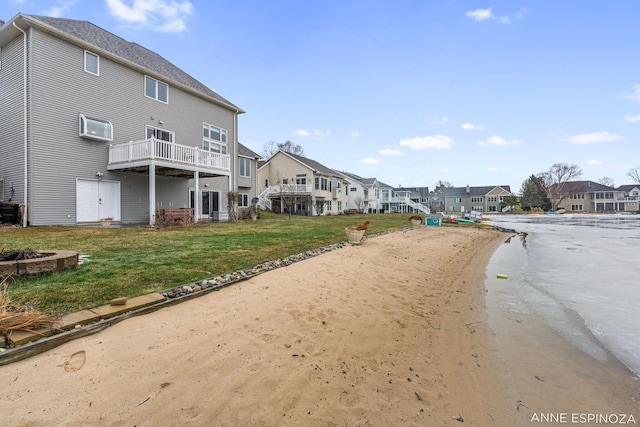 rear view of property featuring a fire pit, a yard, a wall unit AC, and a residential view