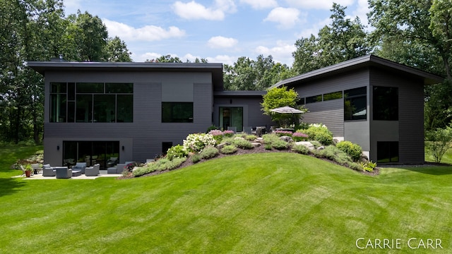 rear view of house featuring a garage, a patio area, an outdoor living space, and a yard