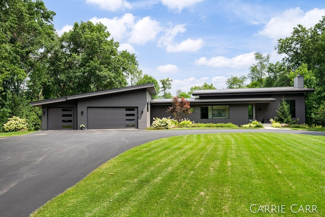 mid-century home featuring a chimney, aphalt driveway, a tiled roof, an attached garage, and a front yard