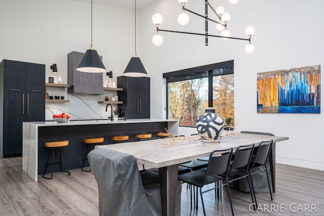 dining room featuring light wood-style flooring, a high ceiling, and baseboards