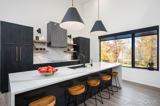 kitchen with a sink, backsplash, light stone countertops, open shelves, and pendant lighting