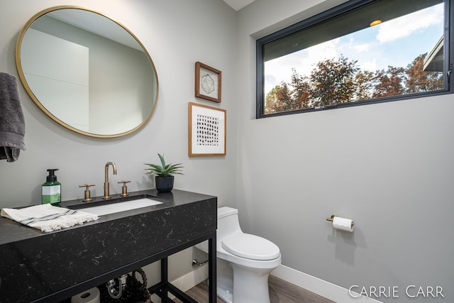 bathroom featuring baseboards, vanity, toilet, and wood finished floors