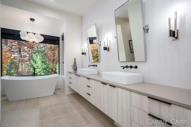 full bath featuring double vanity, a freestanding tub, and a sink