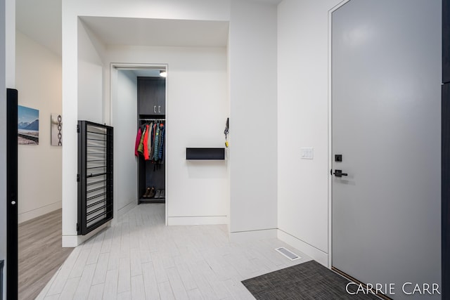 hallway with visible vents, baseboards, and wood finished floors