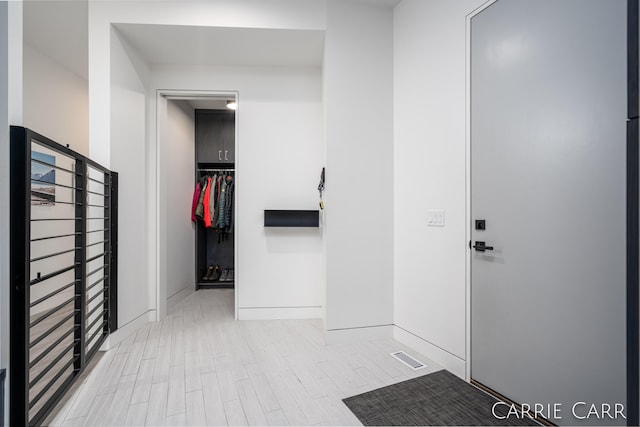 hall featuring visible vents, baseboards, and wood finished floors