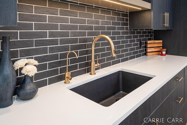 details featuring tasteful backsplash, light countertops, and a sink