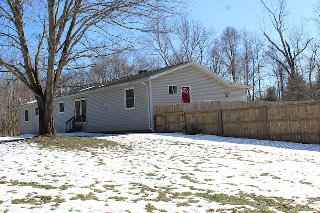 snow covered back of property with entry steps and fence