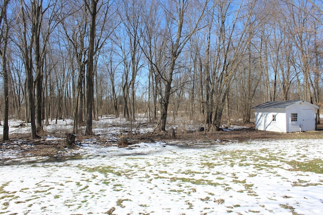 yard covered in snow featuring an outdoor structure and a storage shed