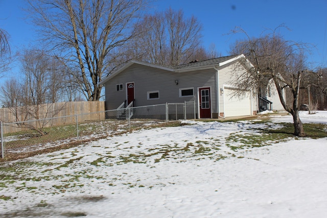 view of snow covered exterior featuring a garage and fence