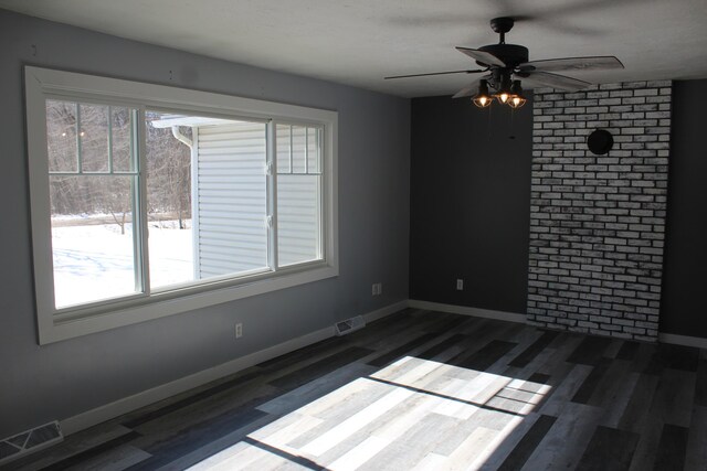 spare room with dark wood-style floors, visible vents, and baseboards