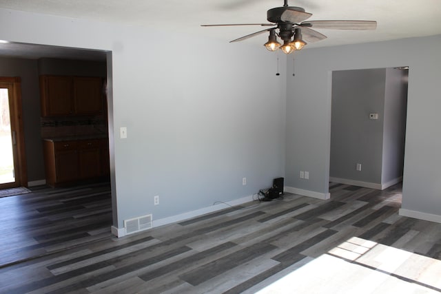 interior space with a ceiling fan, visible vents, baseboards, and wood finished floors