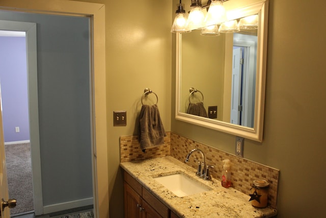 bathroom featuring baseboards, decorative backsplash, and vanity