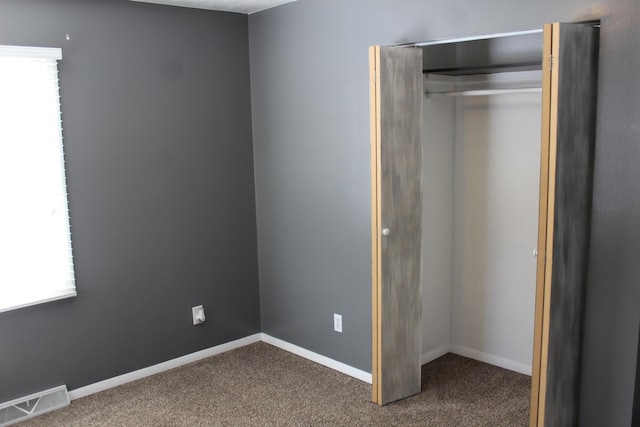 unfurnished bedroom featuring a closet, visible vents, baseboards, and carpet flooring