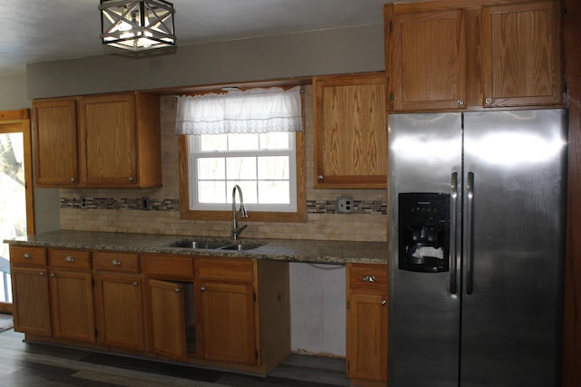 kitchen featuring a sink, decorative backsplash, stainless steel fridge, and brown cabinets