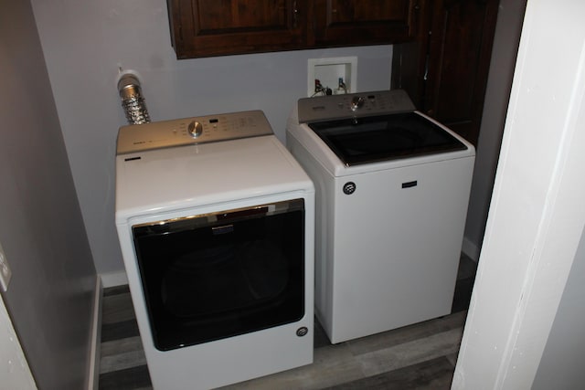 washroom featuring washer and clothes dryer, cabinet space, and light wood-style floors