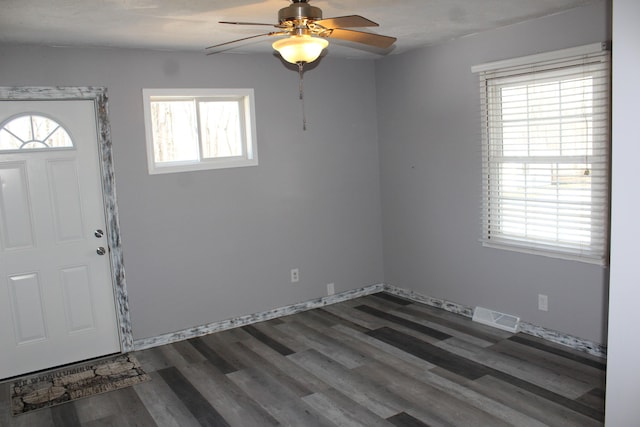 foyer entrance featuring a ceiling fan, baseboards, visible vents, and dark wood-style flooring