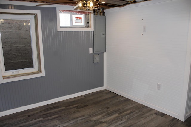 below grade area with dark wood-style floors, electric panel, and baseboards