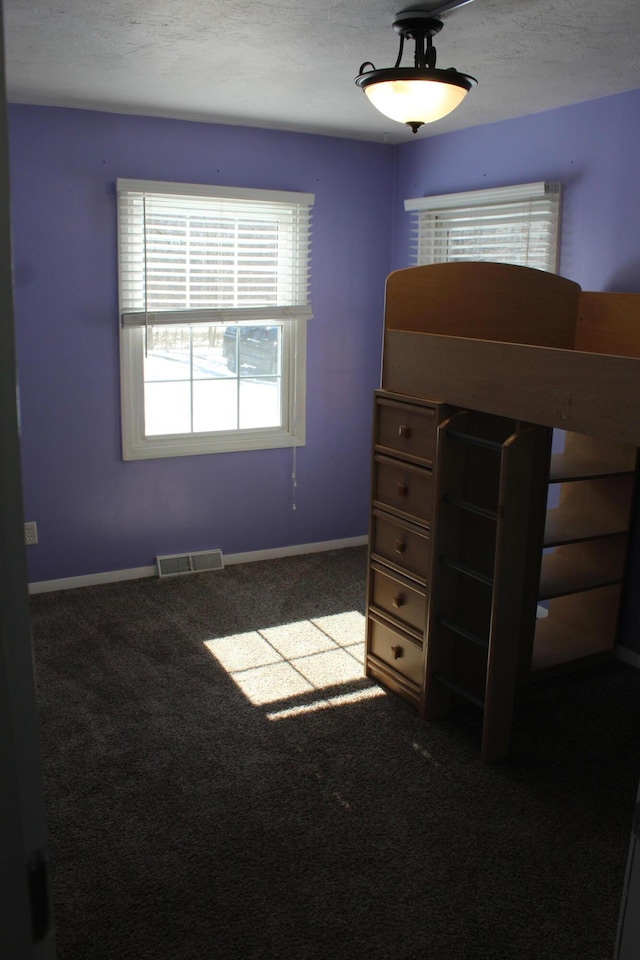 unfurnished bedroom with baseboards, a textured ceiling, visible vents, and carpet flooring