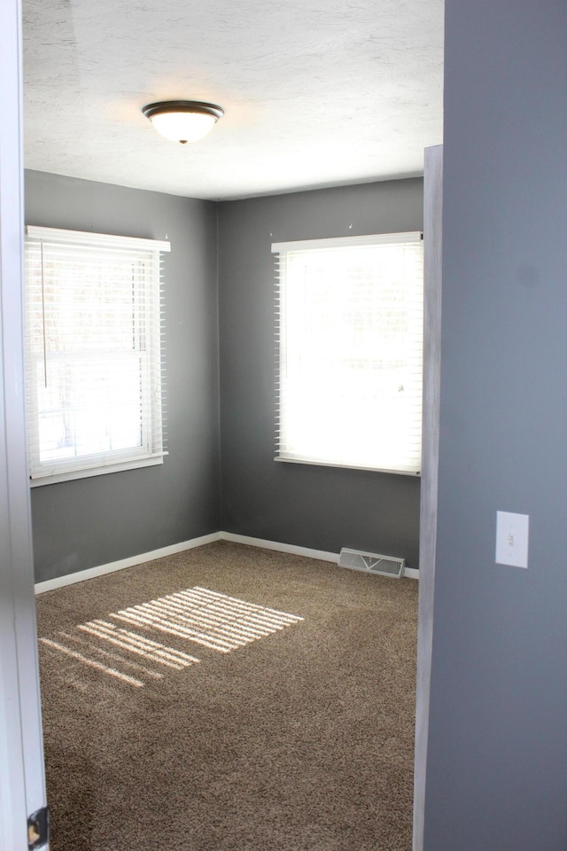 carpeted spare room with visible vents and baseboards