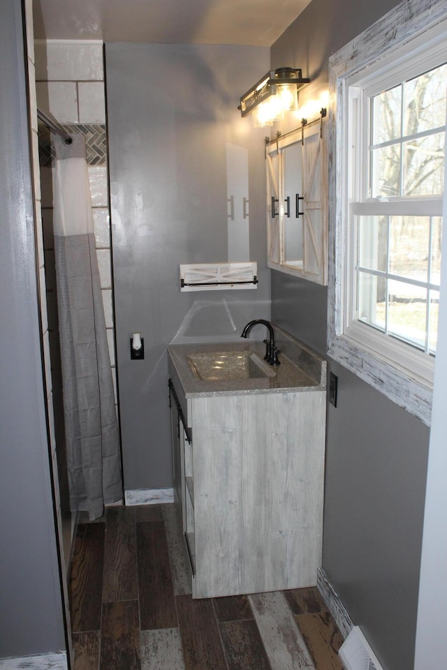 bathroom with curtained shower, wood finished floors, vanity, and baseboards