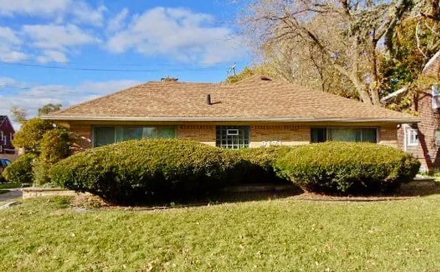 view of home's exterior with a shingled roof, a lawn, and brick siding