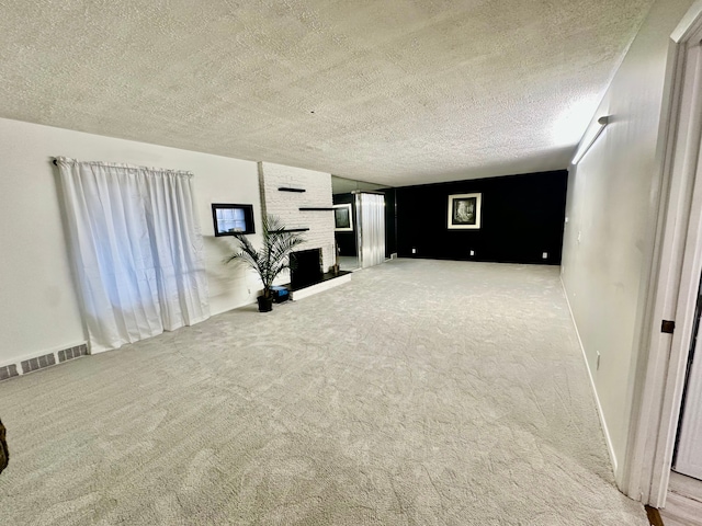 unfurnished living room with a textured ceiling, carpet, visible vents, and a brick fireplace