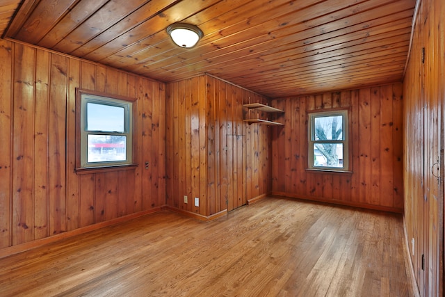 empty room featuring light wood-type flooring, wood ceiling, plenty of natural light, and baseboards