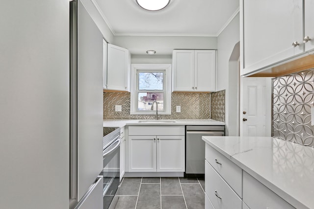 kitchen with appliances with stainless steel finishes, a sink, white cabinets, and crown molding