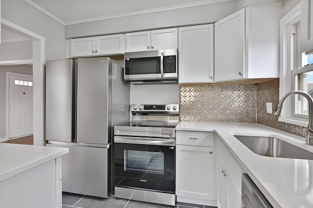 kitchen with stainless steel appliances, tasteful backsplash, light countertops, white cabinets, and a sink