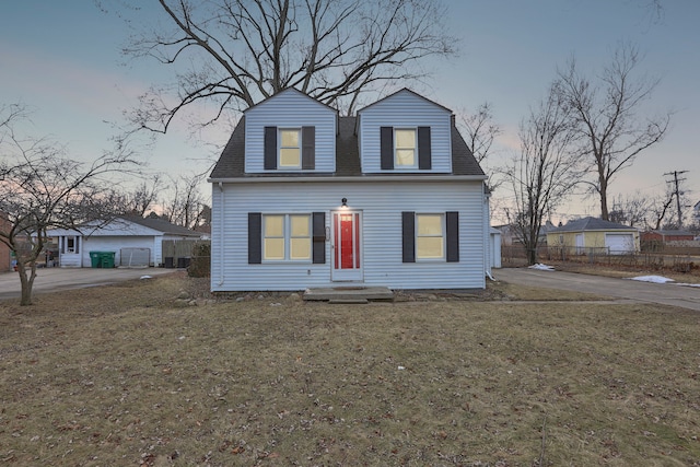 colonial inspired home with a shingled roof, a lawn, and fence