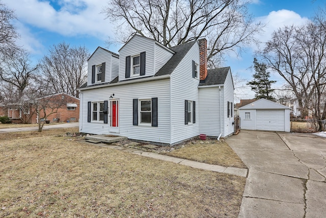 new england style home featuring an outbuilding, a garage, driveway, a front lawn, and a chimney