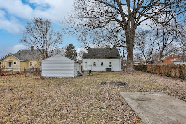 back of house featuring a fenced backyard, an outdoor structure, central AC, and a lawn