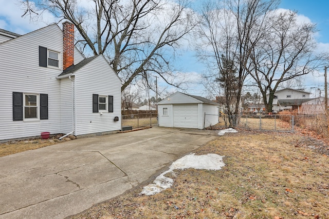 view of side of property with a garage, fence, concrete driveway, and an outbuilding