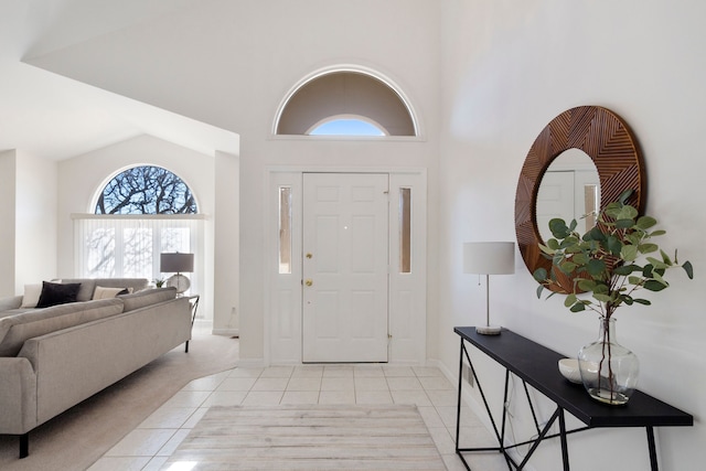 entrance foyer with light tile patterned floors, baseboards, and high vaulted ceiling