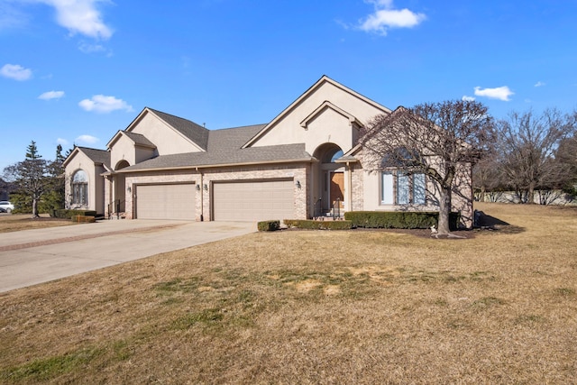 view of front facade with a garage, a front yard, driveway, and stucco siding