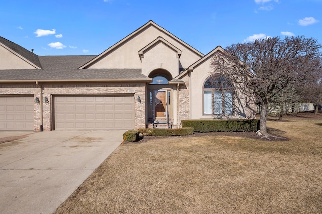 view of front of home with stucco siding, a front lawn, driveway, roof with shingles, and a garage