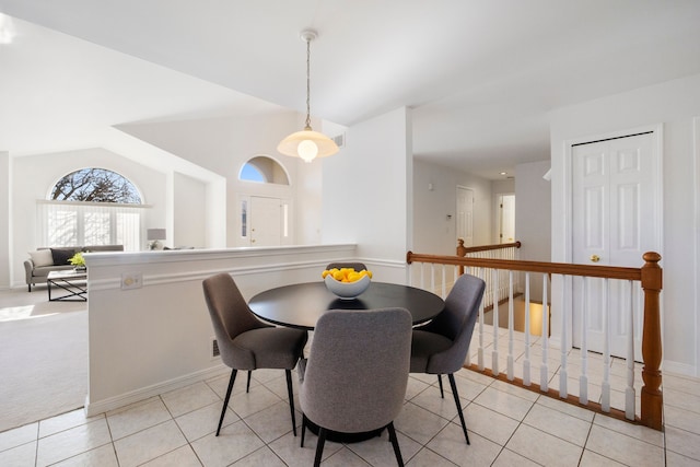 dining space with light tile patterned floors, baseboards, light colored carpet, and vaulted ceiling