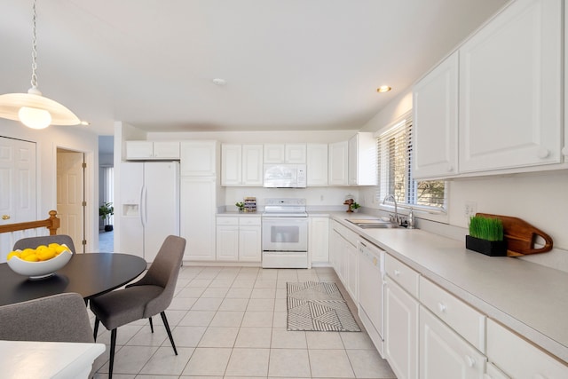 kitchen featuring pendant lighting, a sink, white appliances, light countertops, and light tile patterned floors