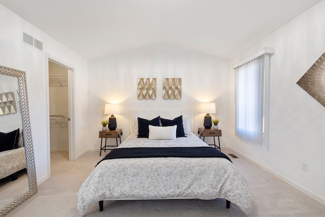 carpeted bedroom featuring visible vents, a walk in closet, baseboards, and vaulted ceiling