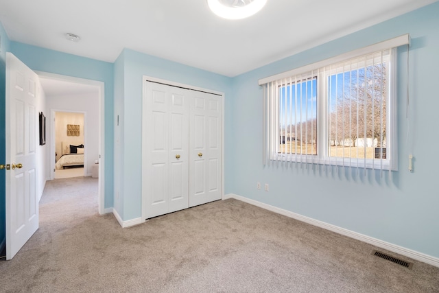 unfurnished bedroom with a closet, visible vents, baseboards, and carpet