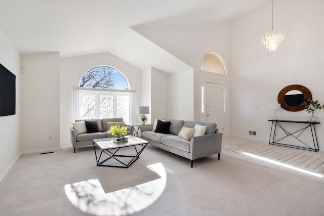 living area featuring light colored carpet, visible vents, a chandelier, and high vaulted ceiling