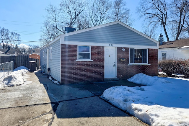 view of front of home featuring driveway, brick siding, and fence