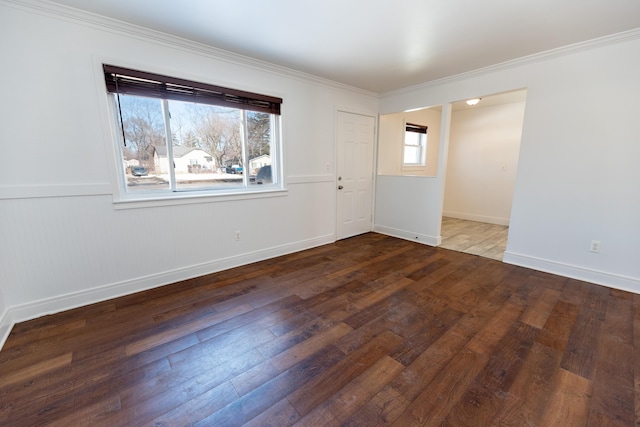 empty room with baseboards, hardwood / wood-style floors, and crown molding