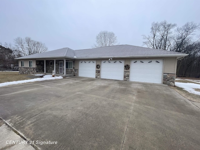 ranch-style home featuring roof with shingles, concrete driveway, covered porch, a garage, and stone siding