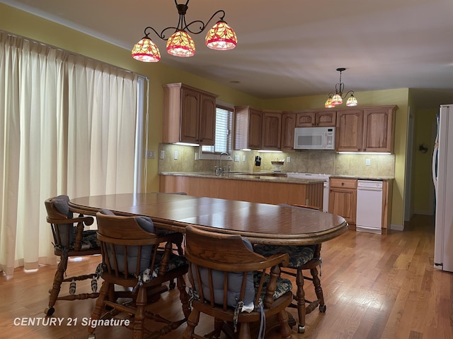 kitchen featuring white appliances, backsplash, light wood-style flooring, and decorative light fixtures